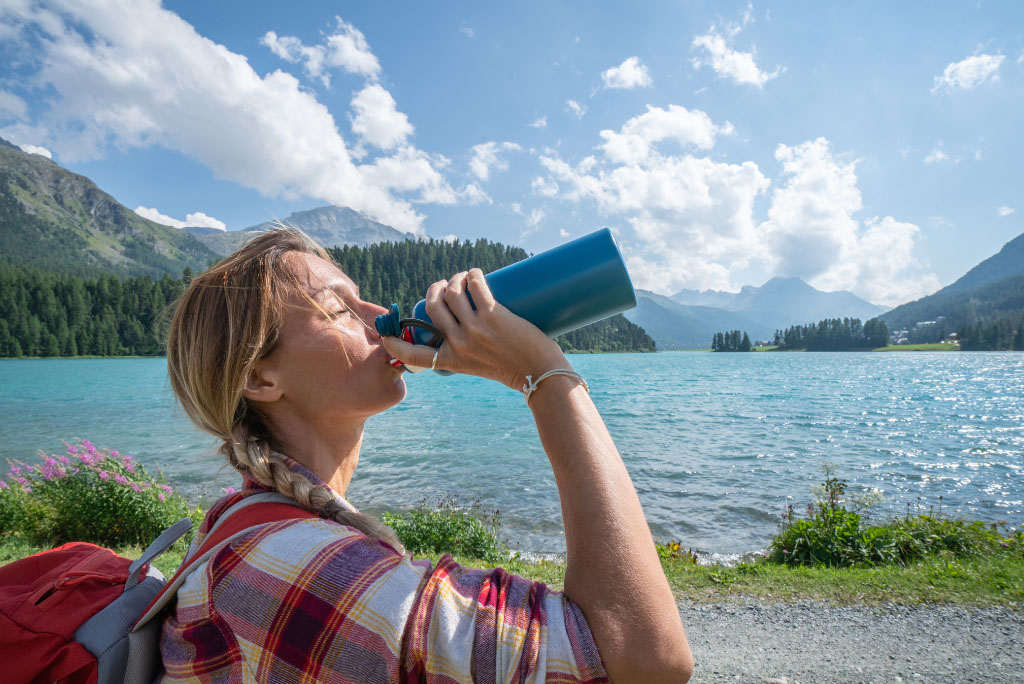 femme qui boit de l'eau dans une bouteille nature voyage